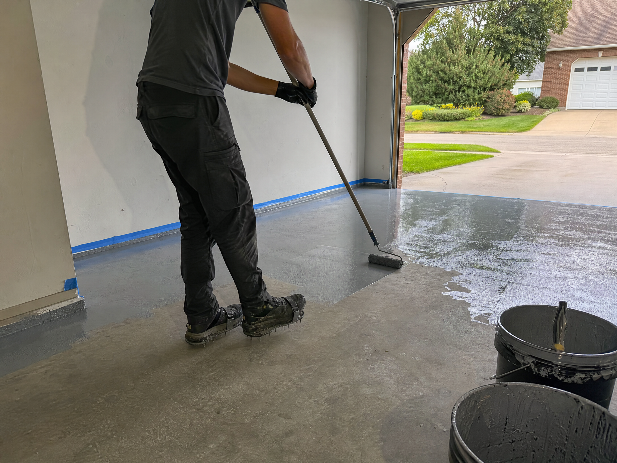 Installer applying an epoxy coating to a garage floor with a roller